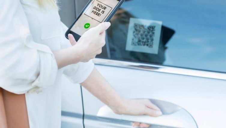 Imagem de uma mulher tentando abrir a porta de um carro realizando a leitura de um QR Code