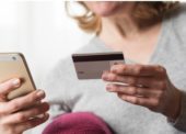 Mulher segura um cartão de crédito com uma mão e o telefone celular com outra mão para fazer um pagamento digital