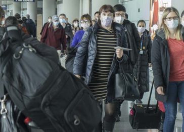 Imagem de pessoas usando máscara no corredor de um aeroporto